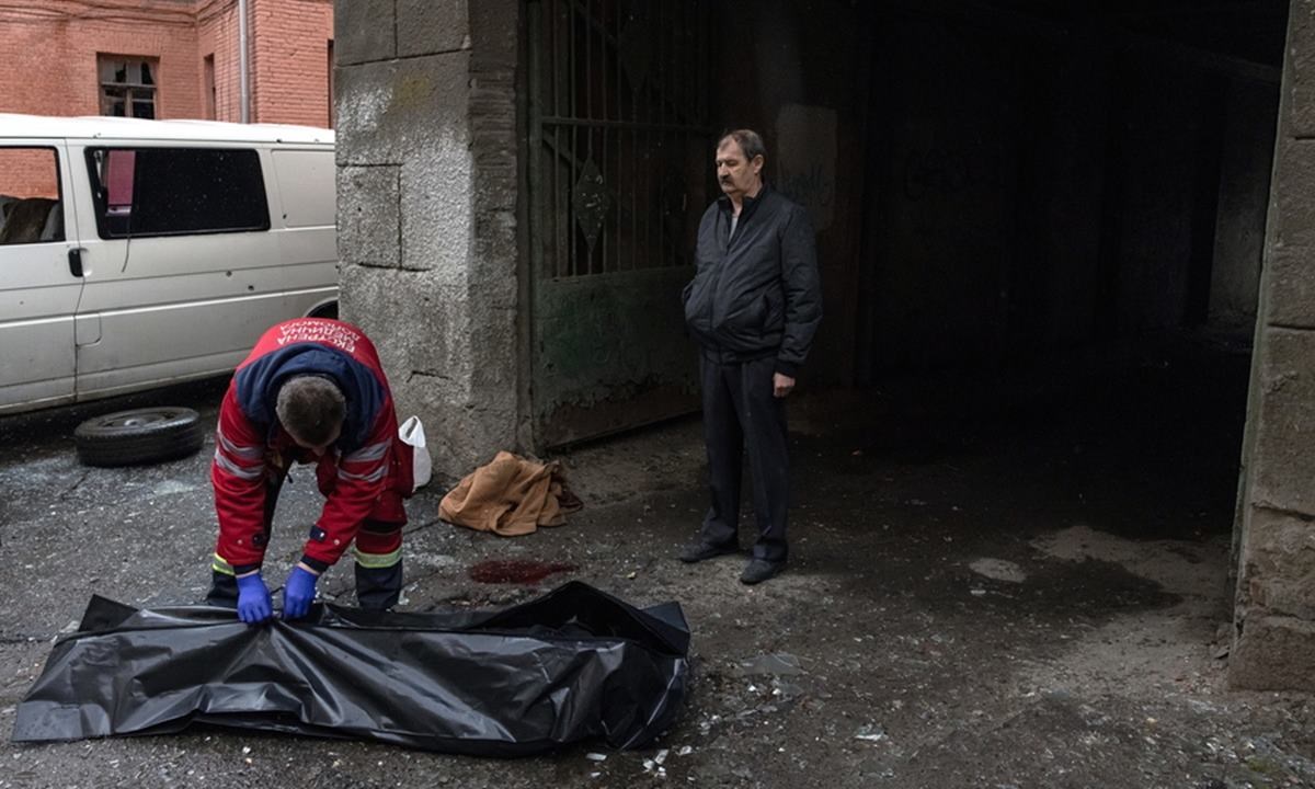 un sanitario chiude un sacco per cadaveri a Kharkiv (foto Ansa)