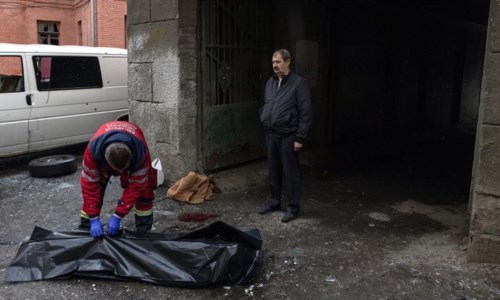 un sanitario chiude un sacco per cadaveri a Kharkiv (foto Ansa)