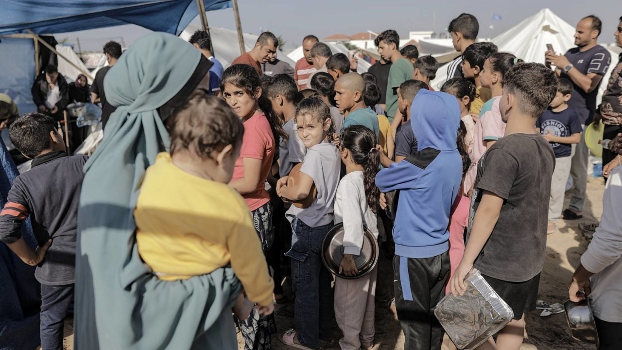 Bambini palestinesi in fila per procurarsi il cibo in un centro Unrwa nel campo profughi di Khan Yunis