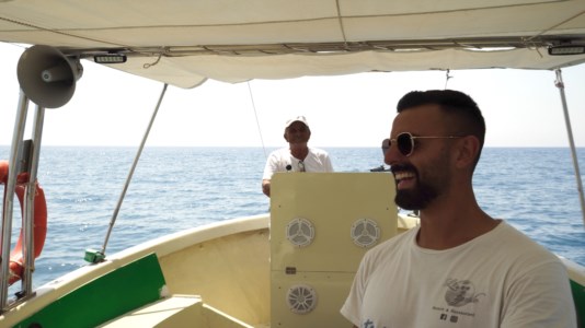 Antonio Manco sorridente insieme al suo papà, sulla piccola imbarcazione di famiglia