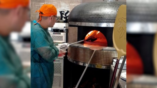 Uno dei ragazzi del centro Teniamoci per mano inforna la pizza appena farcita